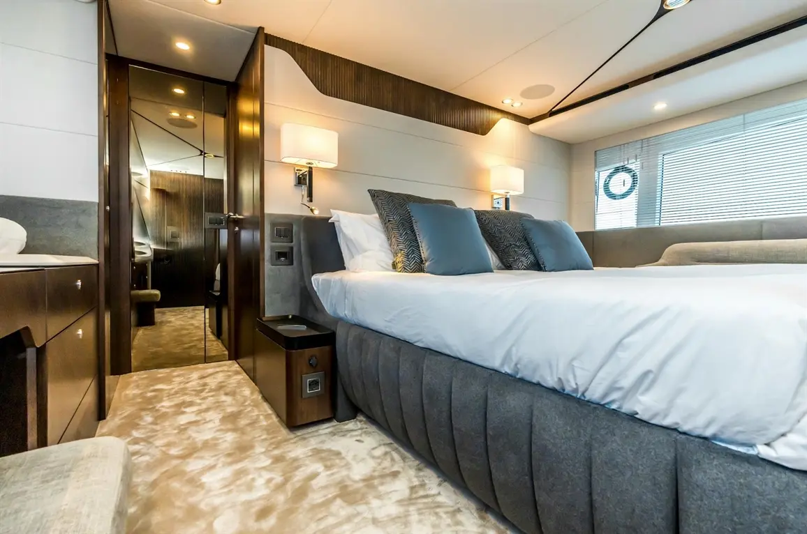 Luxurious bedroom with a large bed, decorative pillows, stylish lighting, and a mirrored wardrobe door reflecting the interior.